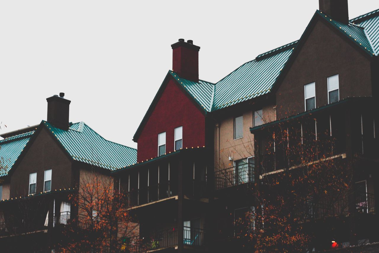 Modern urban apartment buildings with distinctive teal metal roofs and balconies.