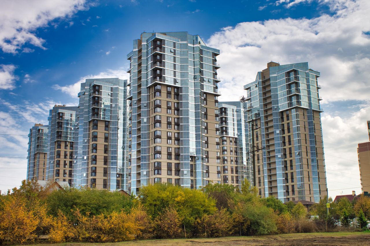 Tall modern residential skyscrapers with reflective glass windows against a vibrant blue sky.